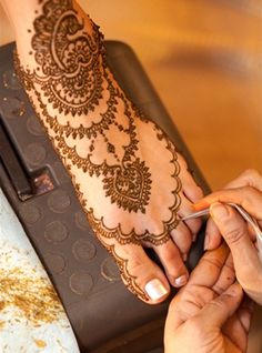 a woman is getting henna done on her hand