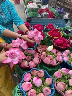 a woman is selling flowers at an outdoor market