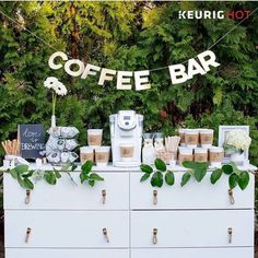 a coffee bar is set up on a dresser with greenery and signs above it