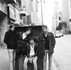 four young men are sitting on the back of a dumpster in an urban setting