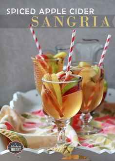 two glasses filled with drinks sitting next to each other on a white plate and table cloth