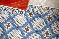 a red rug is laying on the floor next to a blue and white mosaic tile