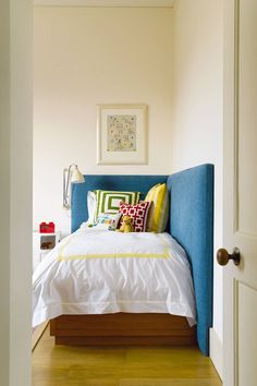 a bed sitting in the middle of a bedroom next to a doorway with a blue headboard