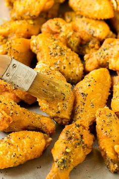 a spatula being used to stir chicken wings with seasoning on them in a pan