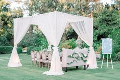 an outdoor wedding setup with white drapes and greenery