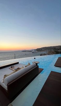 a couch sitting on top of a wooden floor next to a swimming pool near the ocean