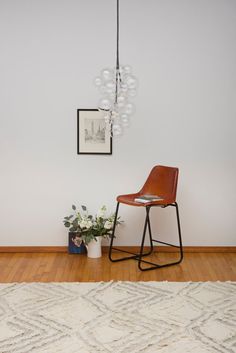 a chair sitting on top of a wooden floor next to a vase with flowers in it