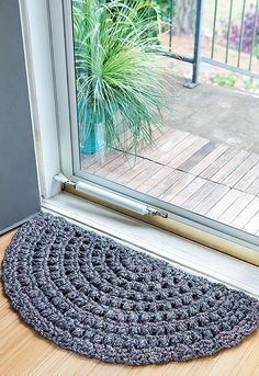 a door mat on the floor next to an open window with a potted plant