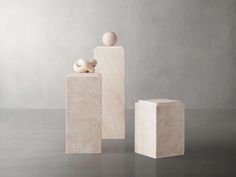 three white sculptures sitting on top of each other in front of a gray wall and floor