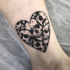 a couple of skulls in the shape of a heart on someone's arm with black ink