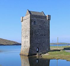 an old brick tower sitting in the middle of a body of water next to a hill