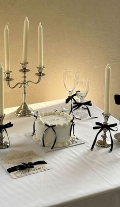 a white table topped with a cake and candles next to wine glasses on top of it