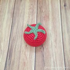 a crocheted strawberry sitting on top of a wooden floor