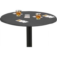 two glasses of beer are sitting on a round table with playing cards around the edge