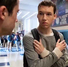 two young men standing next to each other in a room with blue and white tile flooring