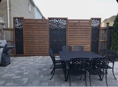 an outdoor dining table and chairs in front of a wooden privacy fence on a brick patio