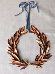 a wreath made out of wood and ribbon on a white tablecloth with a blue bow