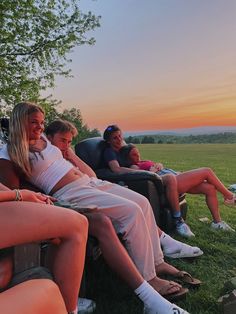 four people are sitting on a bench in the grass