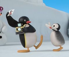 three penguins are standing next to each other and one penguin is holding up a camera