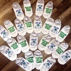 several pairs of white baby shoes with green and blue logos on them, sitting on a wooden floor