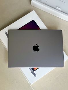 an apple laptop sitting on top of a white box