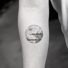 a black and white photo of a person's arm with a circle tattoo on it