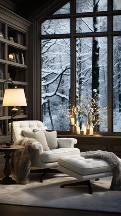 a white chair and ottoman in front of a large window with snowy trees outside it