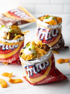 three bags of nachos sitting on top of a table next to some chips