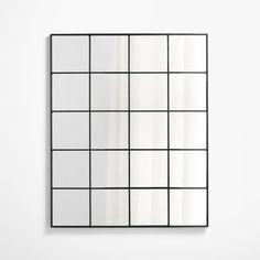 a mirror that is on the wall with squares and lines around it, in front of a white wall