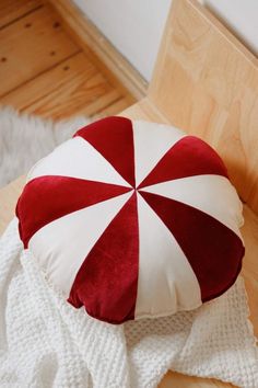 a red and white striped cushion sitting on top of a wooden floor next to a blanket