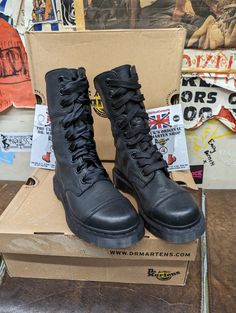 This Dr Martens boot has long been discontinued. We still get requests for them and have come across this one pair. They are the Black Aimilita 9 Hole boot. Finished in a soft brushed leather they will be immediately comfortable. They are a trendy looking boot with a stitched toe cap buckles and straps at the back of the boot so you can fold the boot down which in turn shows off the lining. They are a UK size 3, European 36, ladies USA 5. Alternative High Ankle Boots For Fall, Alternative High Ankle Boots For Streetwear, Winter High-top Steel Toe Boots, Winter Steel Toe Ankle Boots, Steel Toe Ankle Boots For Streetwear, Alternative Style Winter Boots With Round Toe, Edgy Boots With Reinforced Round Toe, Alternative Style Leather Heeled Boots With Round Toe, Edgy Steel Toe Boots With Round Toe