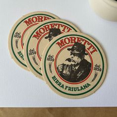 three round stickers with an image of a man drinking from a cup on top of a table