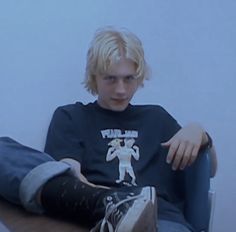 a young man sitting on top of a wooden table