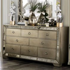 a large mirror sitting on top of a dresser next to a vase filled with flowers