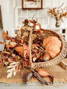 a basket filled with dried leaves and pumpkins