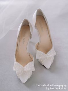 the bride's shoes are all white and have bows on each shoe, along with a veil