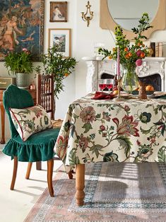 a dining room with a table covered in a flowered cloth and two green chairs