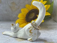 a white cat figurine sitting next to a sunflower