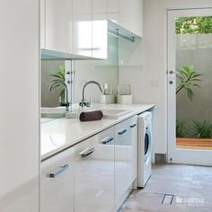 a washer and dryer in a white kitchen with glass doors leading to the outside