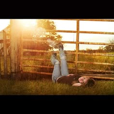 a woman laying in the grass next to a fence