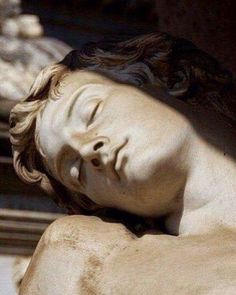 a close up of a statue of a person with his head down and eyes closed