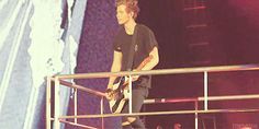 a young man standing on top of a metal railing holding a guitar in his hand