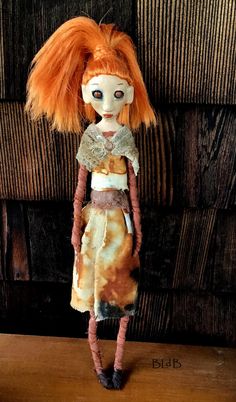 a doll with red hair standing on top of a wooden table next to a wall