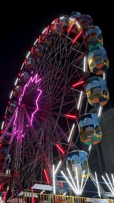 the ferris wheel is brightly lit up at night