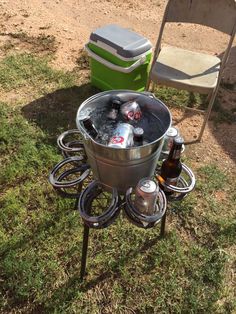 an outdoor grill with beer bottles and coolers on it in the grass next to a lawn chair