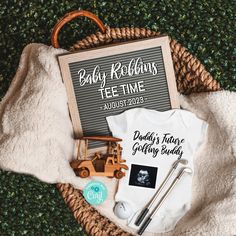 a baby's t - shirt and other items are sitting in a basket on the ground