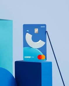 a credit card sitting on top of a blue block next to a light blue wall