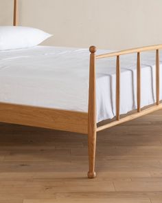 a wooden bed frame with white sheets and pillows