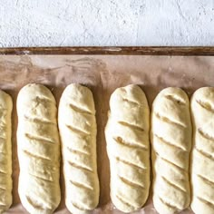 four loaves of bread lined up on a baking sheet in the process of being baked