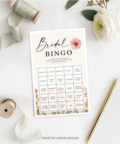 the bridal bingo game is next to some flowers and ribbon on a white table